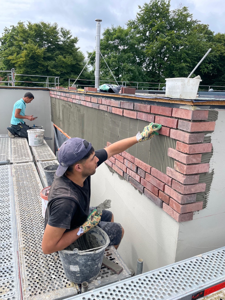 Klinkerverblendung – Facharbeiter beim Anbringen von Klinkerriemchen